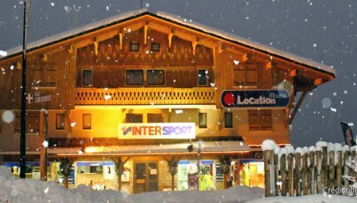 Bâtiment en bois enneigé avec magasin InterSport