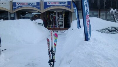 Intersport-Geschäft im Schnee mit Skiern und Werbeflaggen