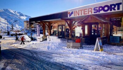 Magasin Inter Sport dans la neige avec des montagnes en arrière-plan.