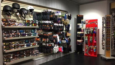 Étagères avec casques de ski, lunettes, gants et accessoires dans un magasin.