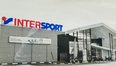 Intersport Filiale mit Hinweisschildern und Parkplatz.