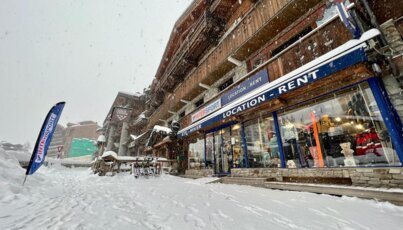 Rue enneigée devant un magasin de location de ski Intersport