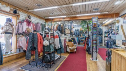 Intérieur d'un magasin de vêtements avec des vêtements, des accessoires et un tapis rouge.